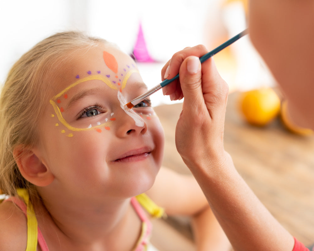 Kind wordt geschminkt met bloemenpenseel tijdens vrolijk schminkfeestje