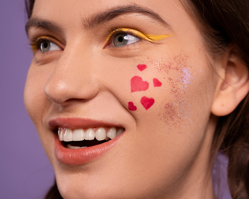 Vrolijke carnaval glitter schmink op gezicht met glitters rond de ogen in roze, blauw en paars