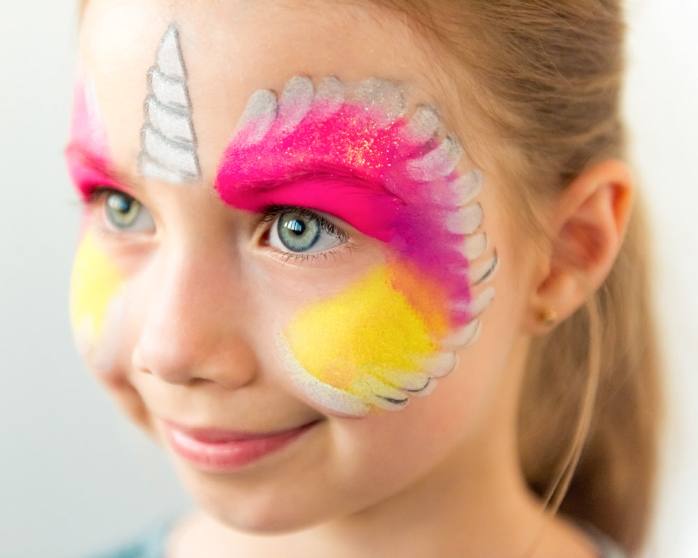 Meisje met pastel schmink als eenhoorn, lachend tijdens een vrolijk kinderfeestje