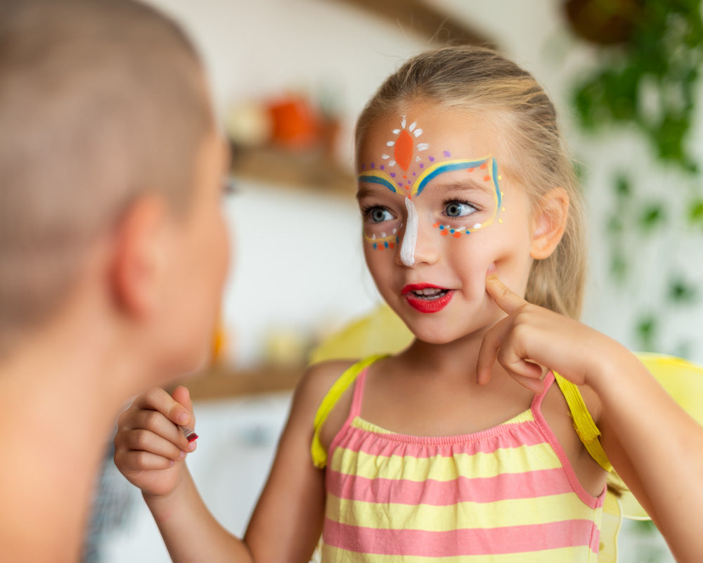 Moeder schminkt haar kind met kleurrijke schmink op waterbasis tijdens een feestje