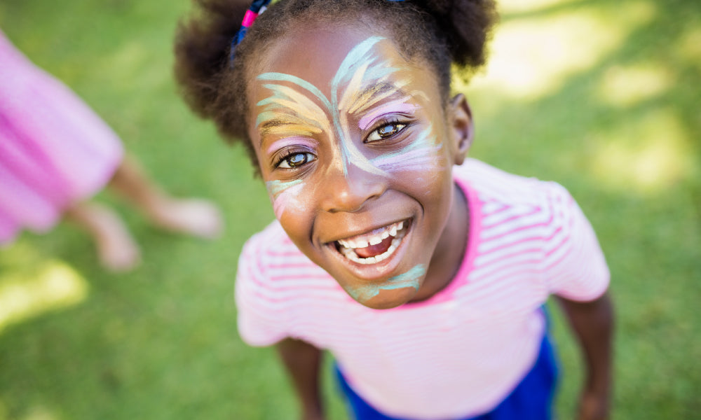 Meisje met kleurrijke schmink op waterbasis in de tuin